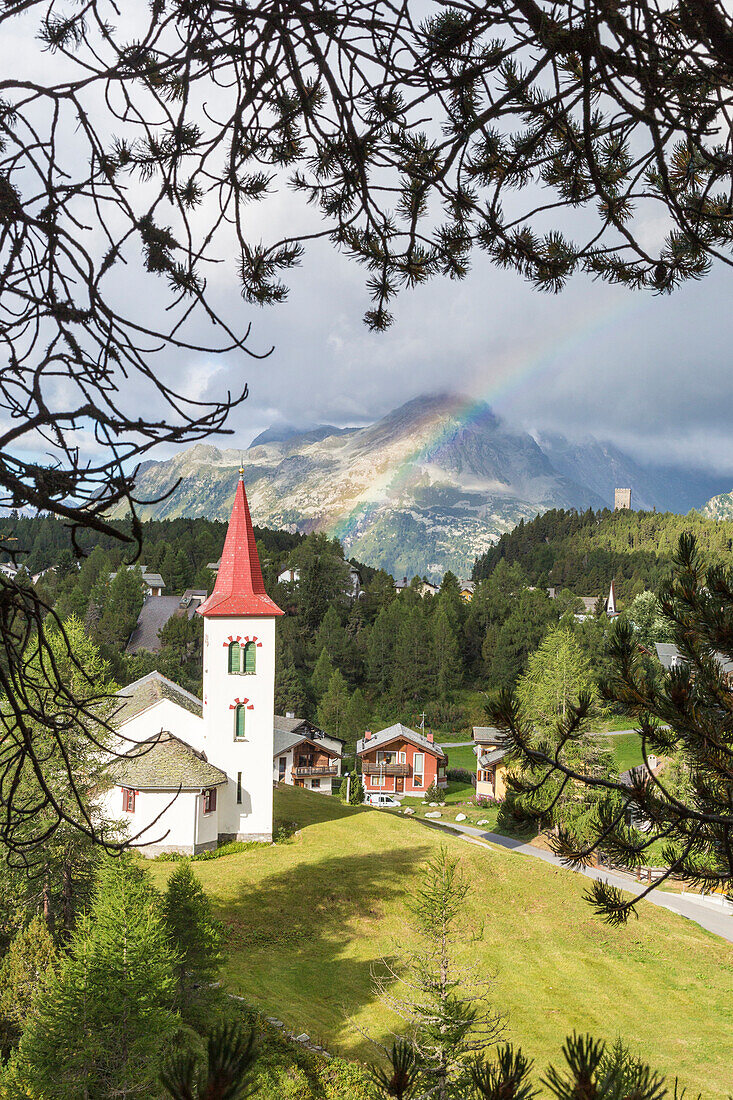 Rainbow over Chiesa Bianca and the village of Maloja, Bregaglia Valley, Canton of Graubunden, Engadin, Switzerland