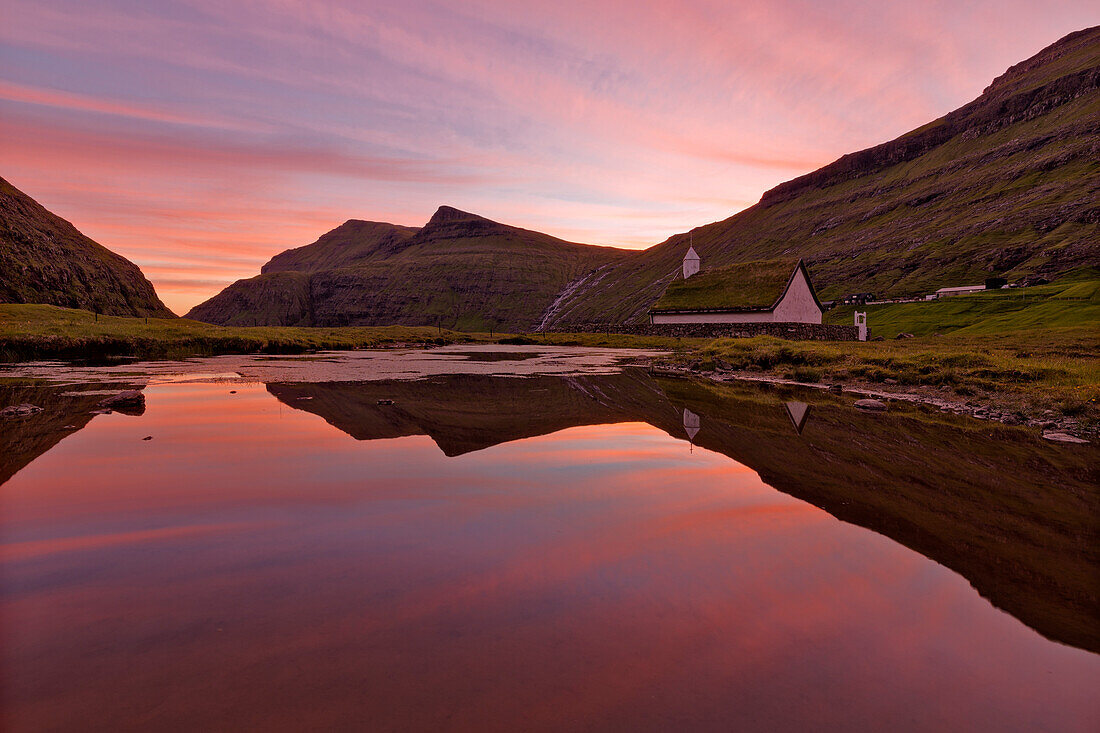 Pink sunset on church surrounded by water, Saksun, Streymoy Island, Faroe Islands