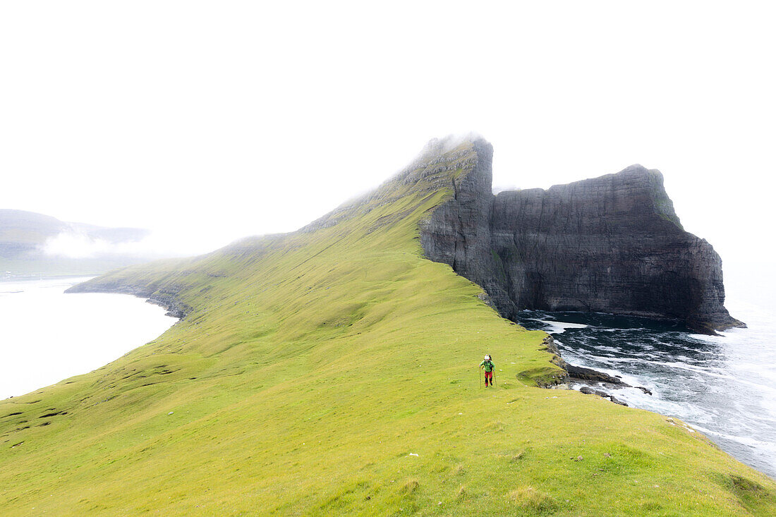 Hiker ventures on cliffs, Drangarnir, Vagar Island, Faroe Islands