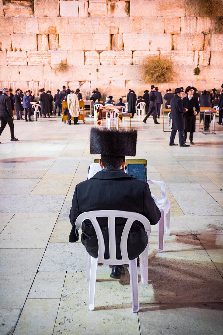 Ultra-orthodox Jewish man reads a torah (holy book) at the Western wall or Wailing wall the holiest place to Judaism in the old city of Jerusalem, Israel, Middle East