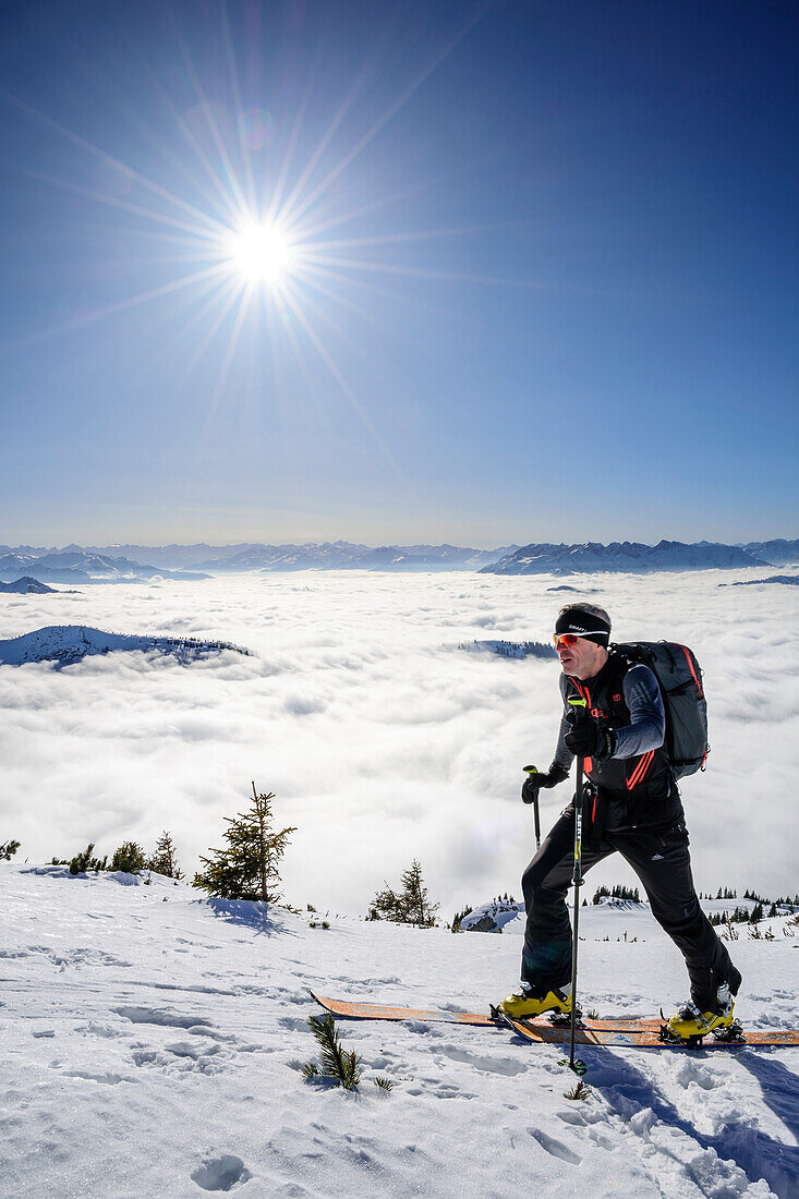 Man backcountry skiing ascending towards Hinteres Sonnwendjoch, fog in the valley, Hinteres Sonnwendjoch, Bavarian Alps, Tirol, Austria