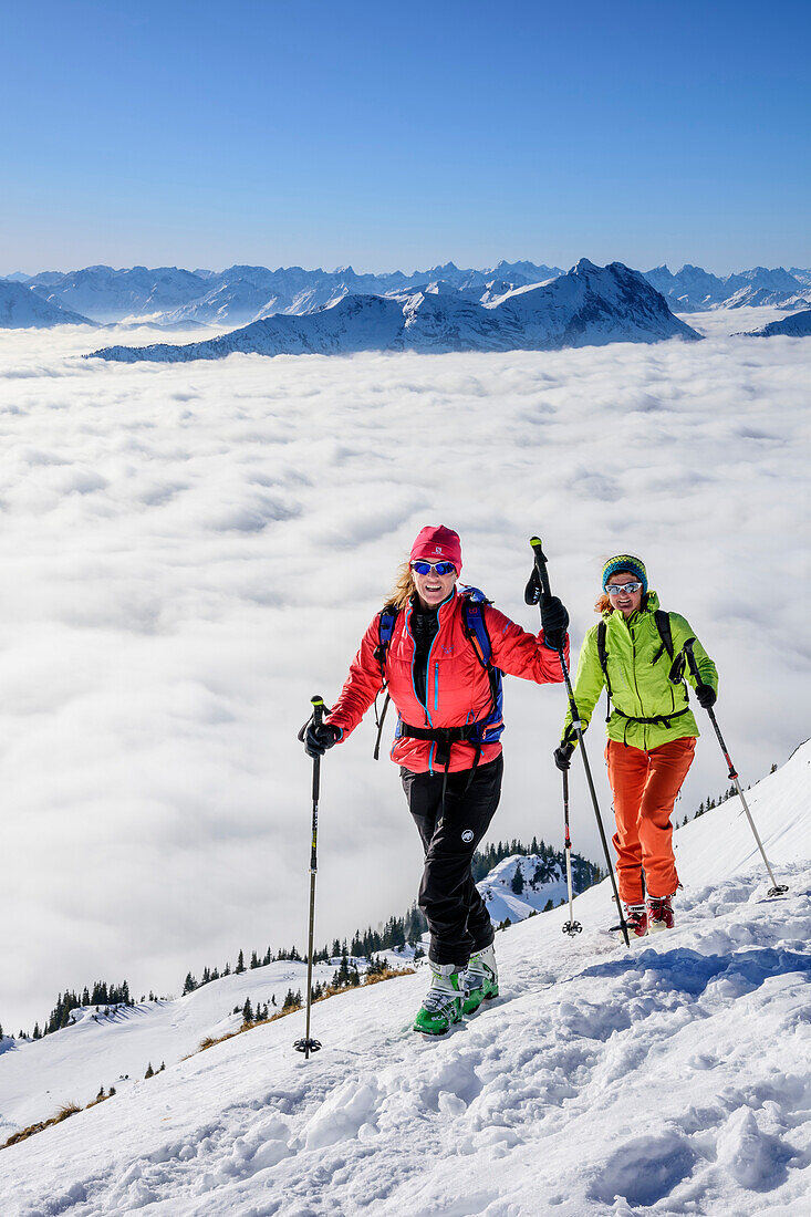 Two women backcountry skiing ascending towards Hinteres Sonnwendjoch, fog in the valley, Hinteres Sonnwendjoch, Bavarian Alps, Tirol, Austria