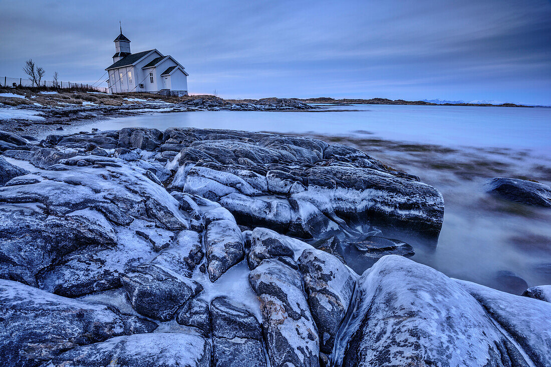 Icy rocks at beach with church in background, Gimsoy, Lofoten, Nordland, Norway
