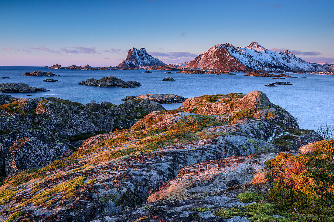 Coast with rocks with snow-covered mountains in background, Lofoten, Nordland, Norway