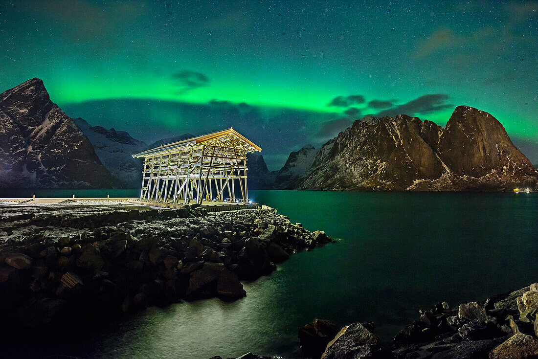 Illuminated shed for drying fish with polar lights and stary sky, northern lights, aurora borealis, Lofoten, Nordland, Norway