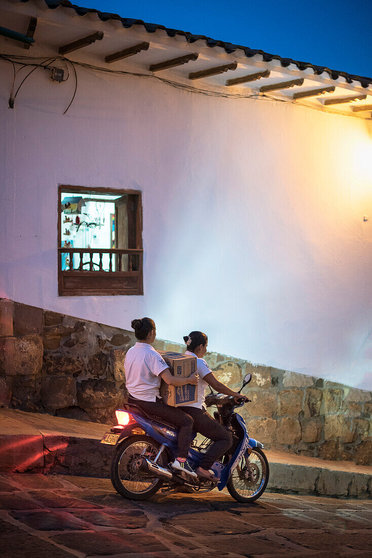zwei einheimische Frauen auf Motorrad transportieren Paket, Barichara, Departmento Santander, Kolumbien, Südamerika