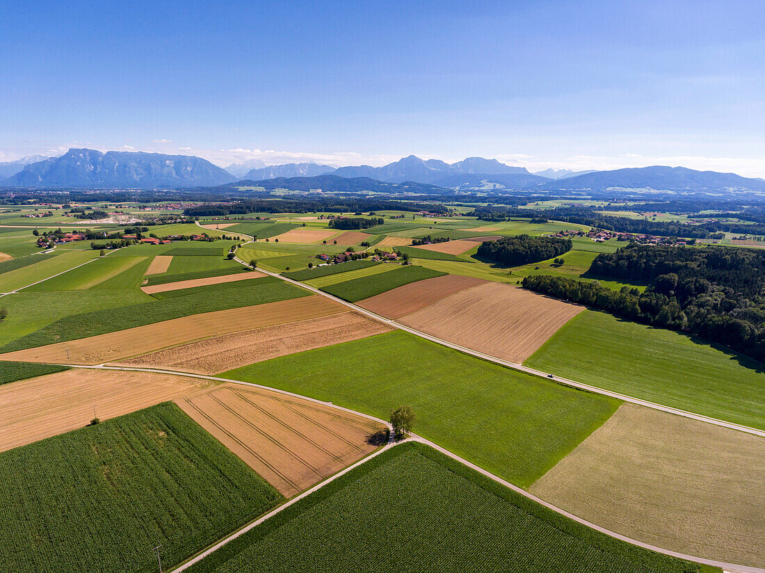 Blick aus der Vogelperspektive über Felder im Gemeindegebiet Saaldorf-Surheim im Berchtesgadener Land, im Hintergrund Hügel und Berge