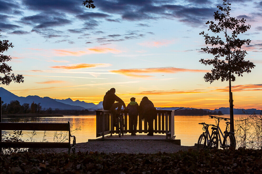 Group of young cyclists in the last evening light on the viewing platform on the Chiemsee in field