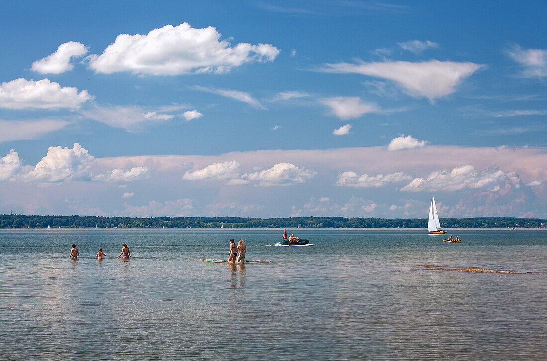 Badebetrieb bei herrlichem Sommerwetter am Chiemsee; Schwimmer und Boote tummeln sich unter weiß-blauem Himmel