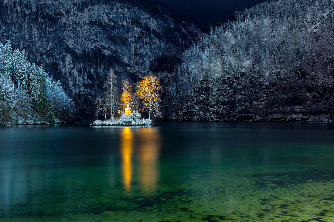 The small island in the Lake Königssee with illuminated John Christian Lieger statue in winter mountain scenery