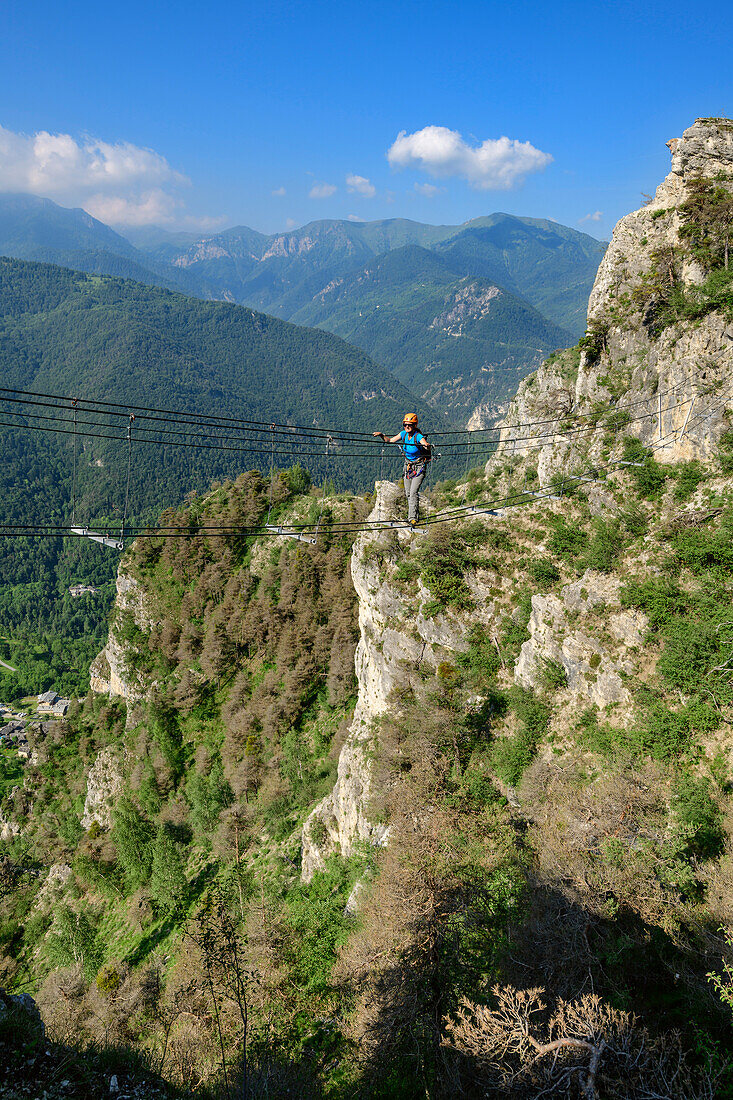Frau am Klettersteig geht über Seilbrücke, Ferrata di Camoglieres, Val Maira, Cottische Alpen, Piemont, Italien