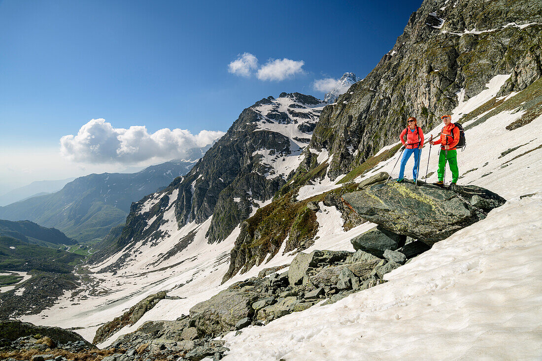 Mann und Frau beim Wandern stehen auf Felsen und blicken ins Tal, Giro di Monviso, Monte Viso, Monviso, Valle di Po, Cottische Alpen, Piemont, Italien