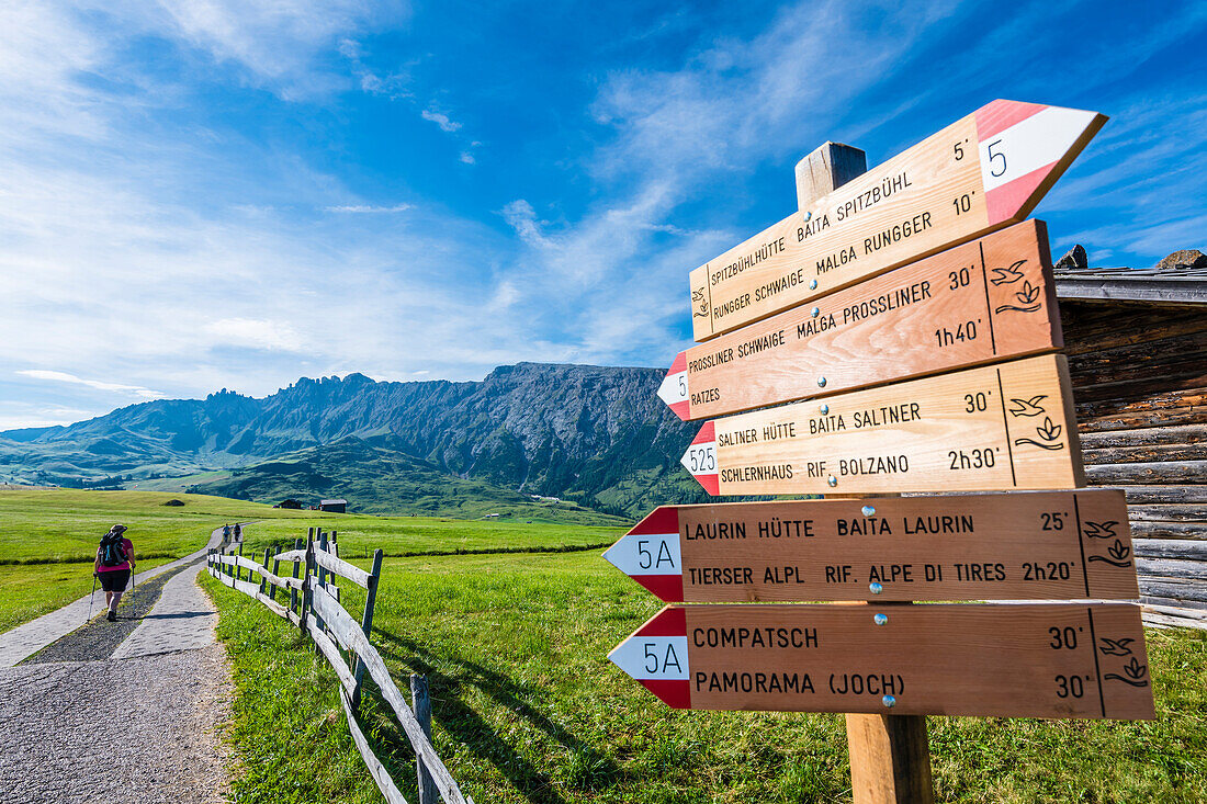 Hiker and signpost in front of  the Schlern Mountains, Compatsch, Alpe di Siusi, South Tyrol, Italy