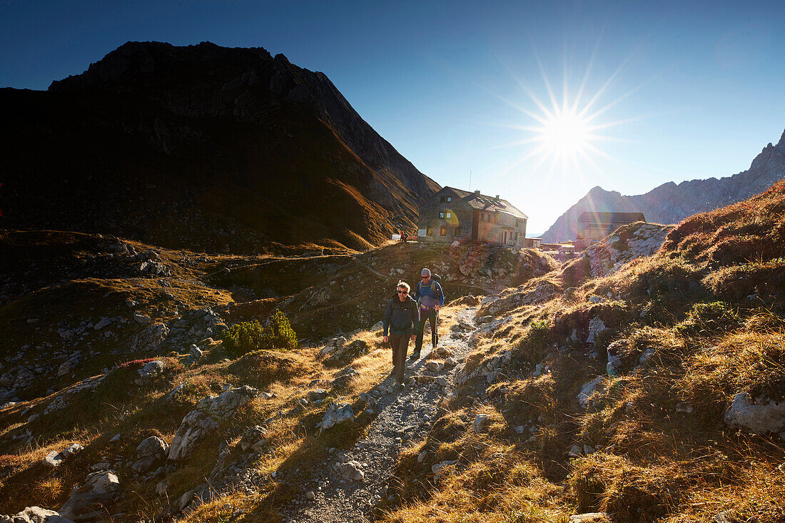 Two hikers leaving Lamsenjoch alpine hut,  Eastern Karwendel Range, Tyrol, Austria