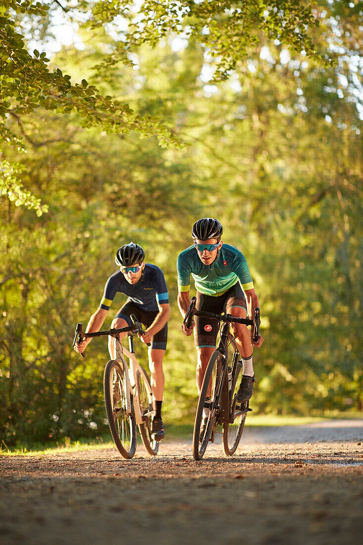 Zwei junge Männer fahren auf Gravel bikes über Feldweg, Münsing, Bayern, Deutschland