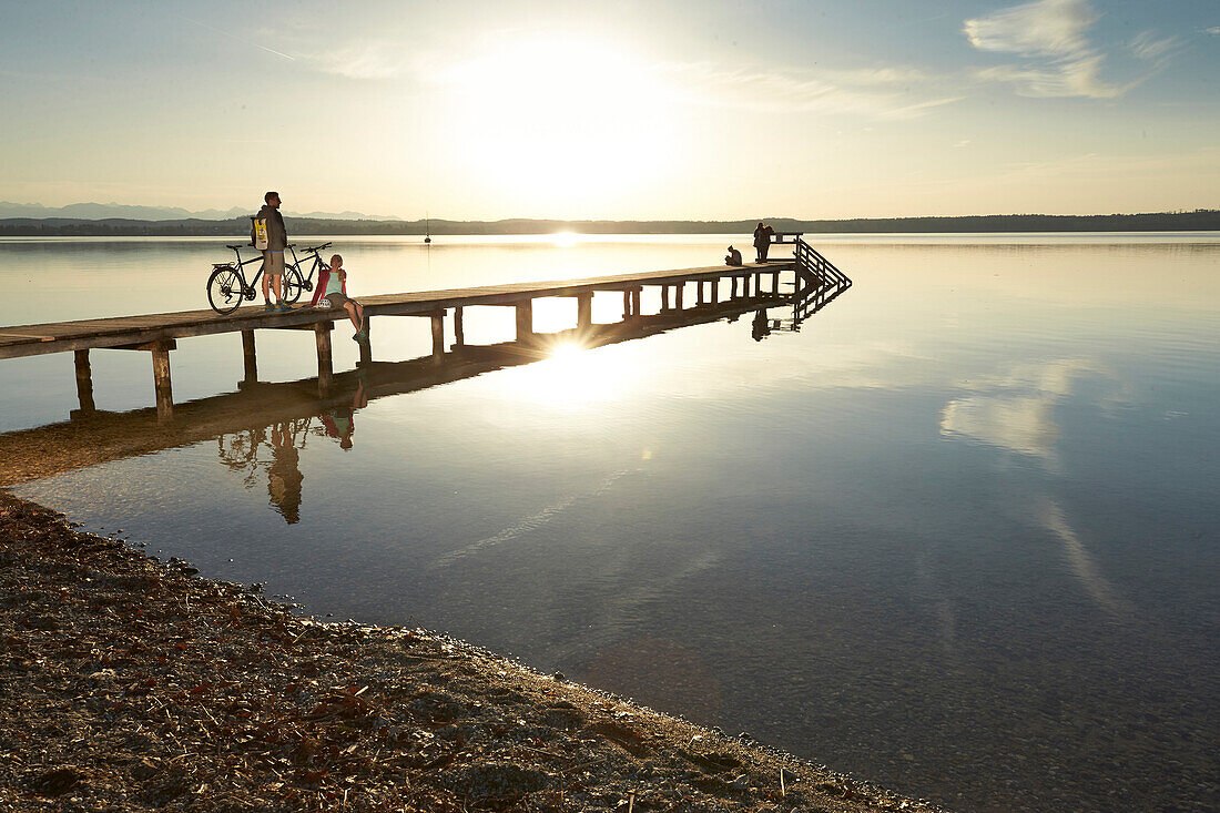 Young  woman and young man with bicycles on a jetty, Muensing, bavaria, germany