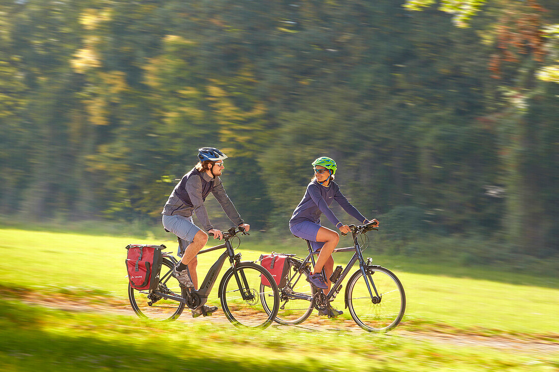 Young  woman on touring bike, young man on touring eBike on tour, Muensing, bavaria, germany