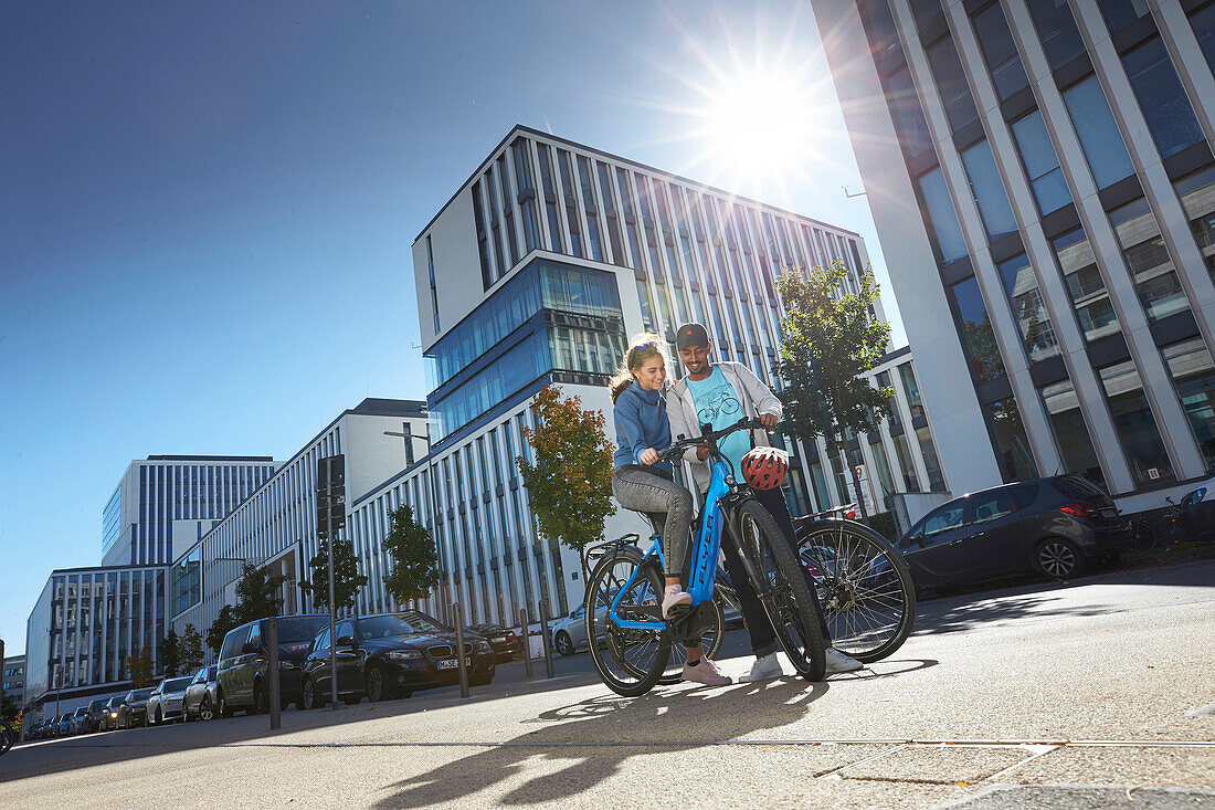 junge Frau und junger Mann Paar auf eBikes in der Stadt, München, Bayern, Deutschland