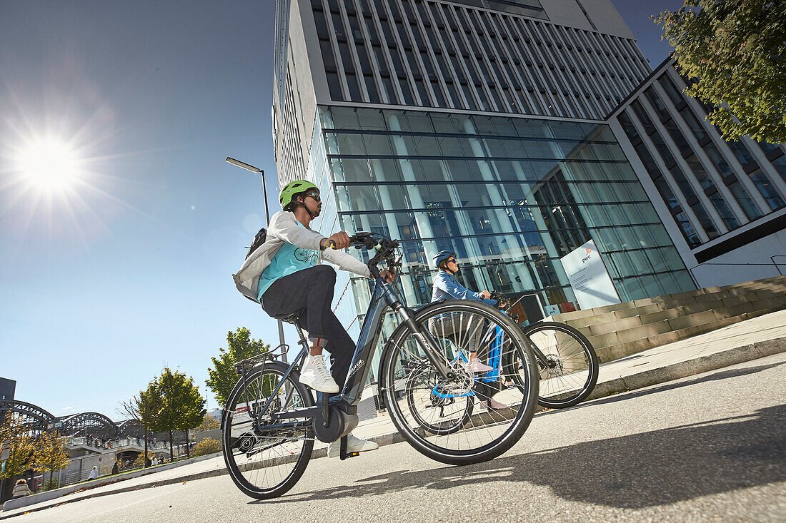 junge Frau und junger Mann Paar auf eBikes in der Stadt, München, Bayern, Deutschland