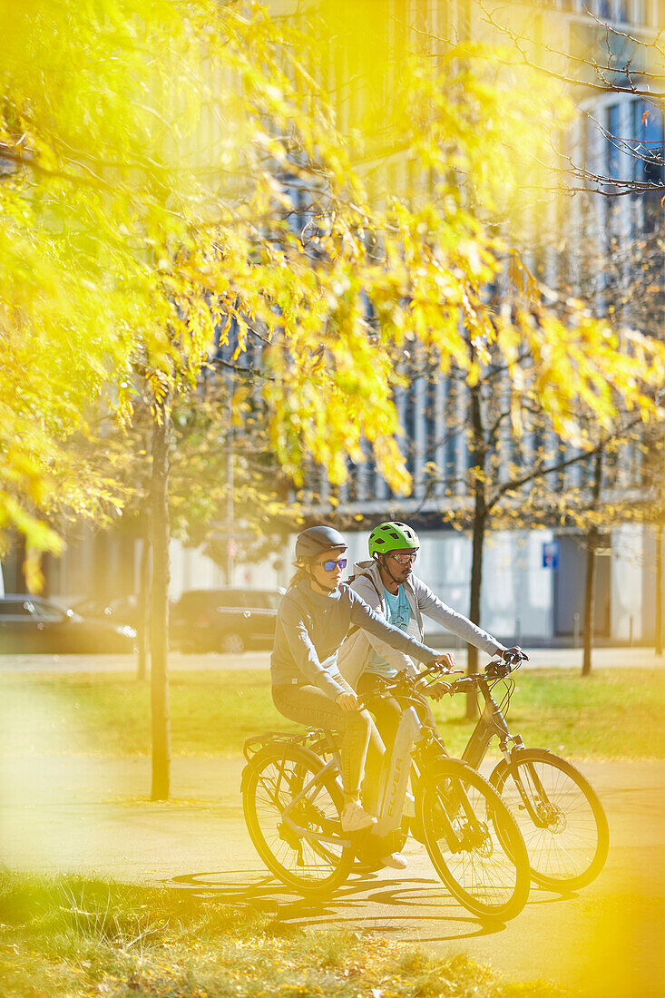 Young  woman young man on eBikes downtown, Munich, bavaria, germany