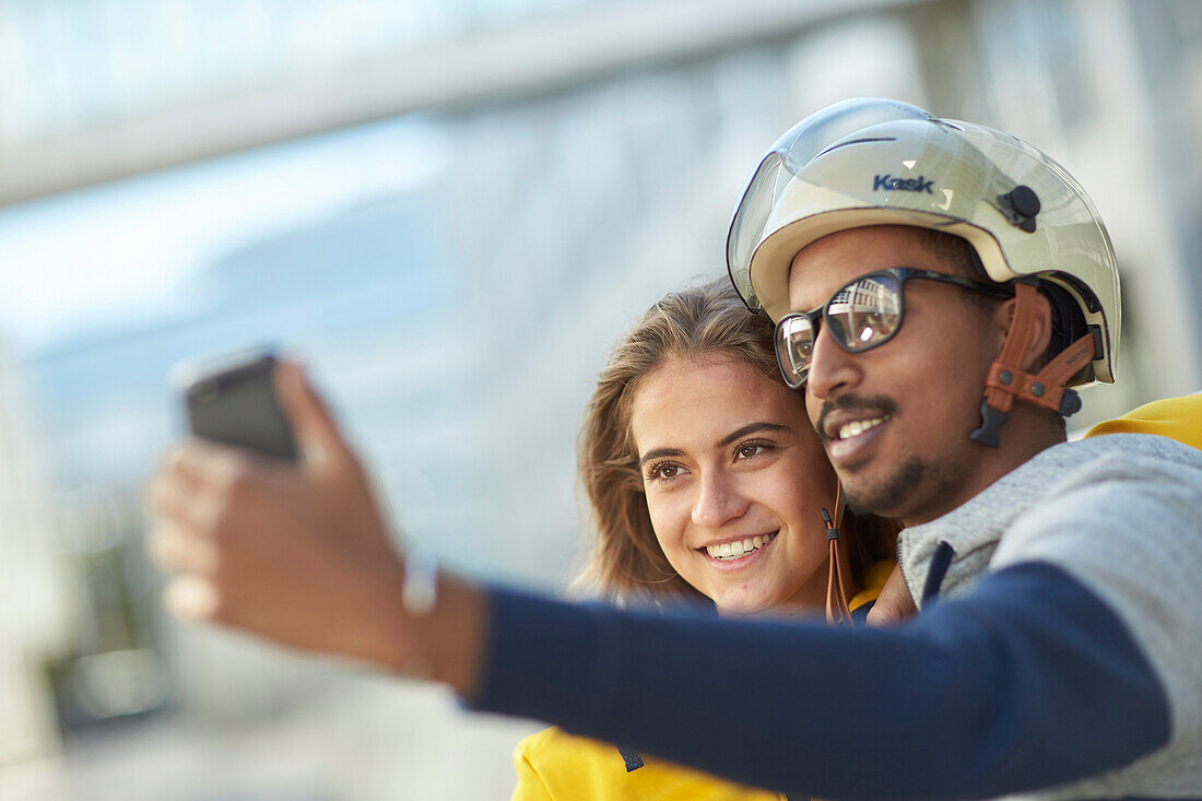 Young  woman young man on eBikes downtown taking Selfie, Munich, bavaria, germany