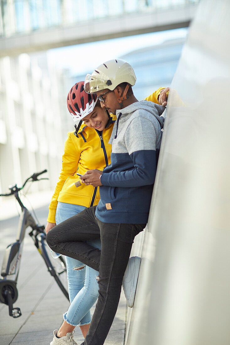 junge Frau und junger Mann mit Handy,Paar mit eBikes in der Stadt, München, Bayern, Deutschland