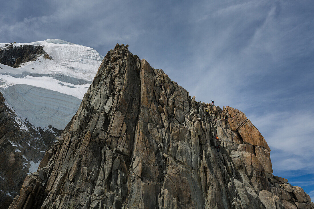 mountaineer following the rocky crest of the lachenal points at the foot of the seracs of the mont-blanc du tacul, massif of the mont-blanc, chamonix-mont-blanc, haute-savoie (74), france