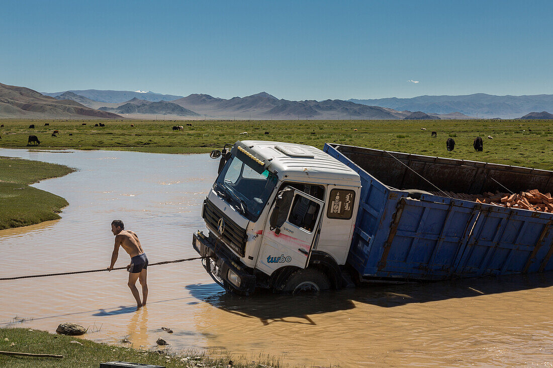 driver trying to get his stuck truck out of a river, altai, bayan-olgii province, mongolia