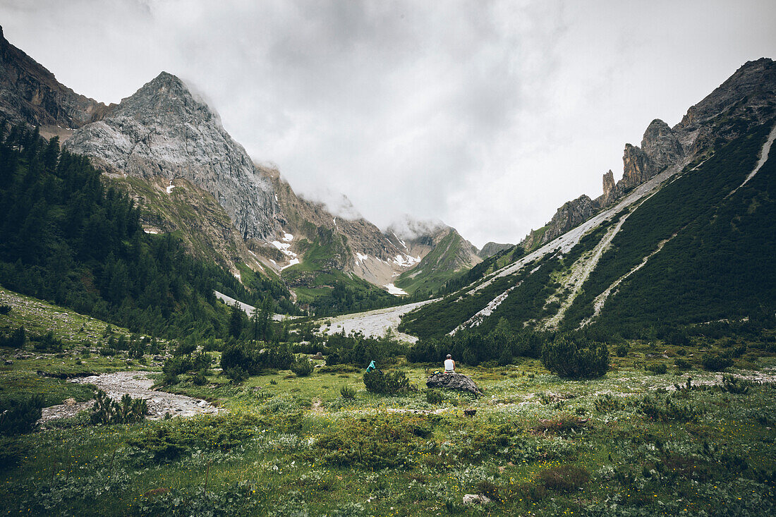 Bergsteiger rastet auf Stein mit Blick auf die Seescharte,E5, Alpenüberquerung, 3. Etappe, Seescharte, Inntal, Tirol, Österreich, Memminger Hütte zur Unterloch Alm