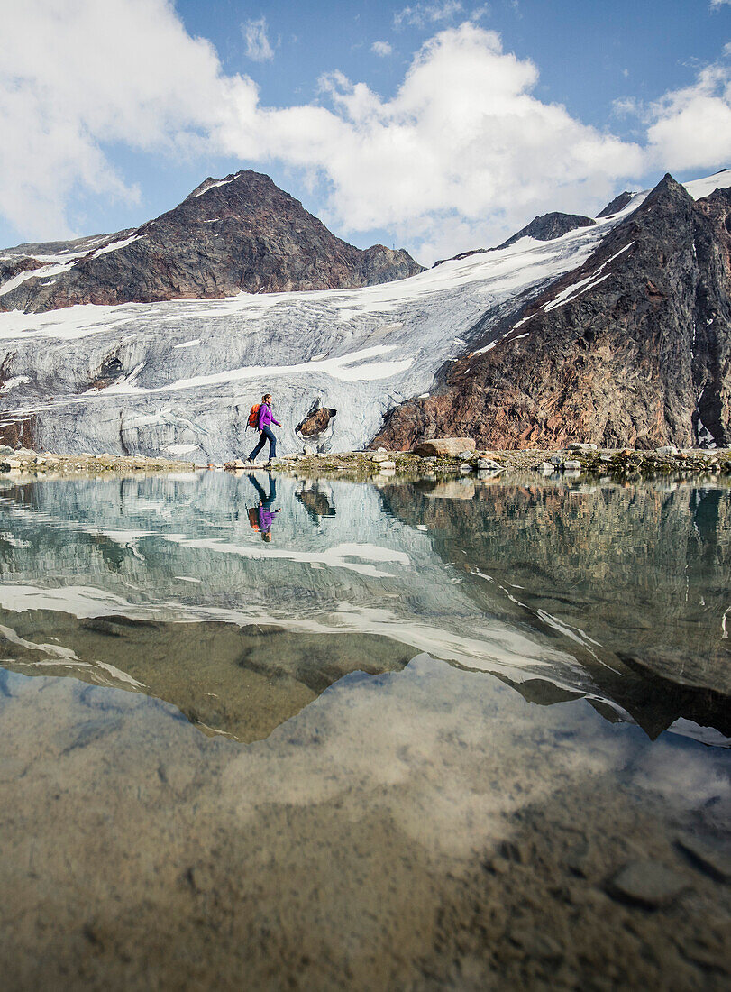 Hiker wanders at a mountain lake with the Pitztal Glacier in the background, E5, Alpenüberquerung, 4th stage, Skihütte Zams,Pitztal,Lacheralm, Wenns, Gletscherstube, Zams to  Braunschweiger Hütte, tyrol, austria, Alps