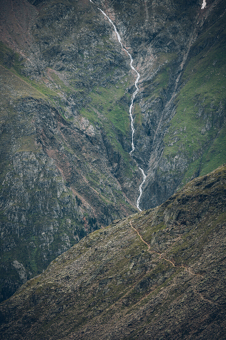 Long distance hiking path with waterfall in the background, E5,Alpenüberquerung,5th stage, Braunschweiger Hütte,Ötztal, Rettenbachferner, Tiefenbachferner, Panoramaweg to Vent, tyrol, austria, Alps
