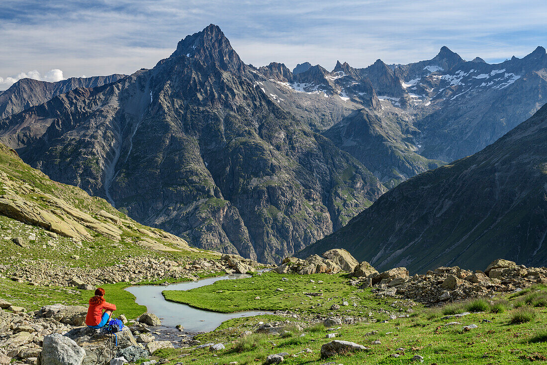 Frau beim Wandern sitzt auf Felsblock und blickt auf Aiguille du Plat de la Selle, am Lac des Bèches, Ecrins, Nationalpark Ecrins, Dauphine, Dauphiné, Hautes Alpes, Frankreich