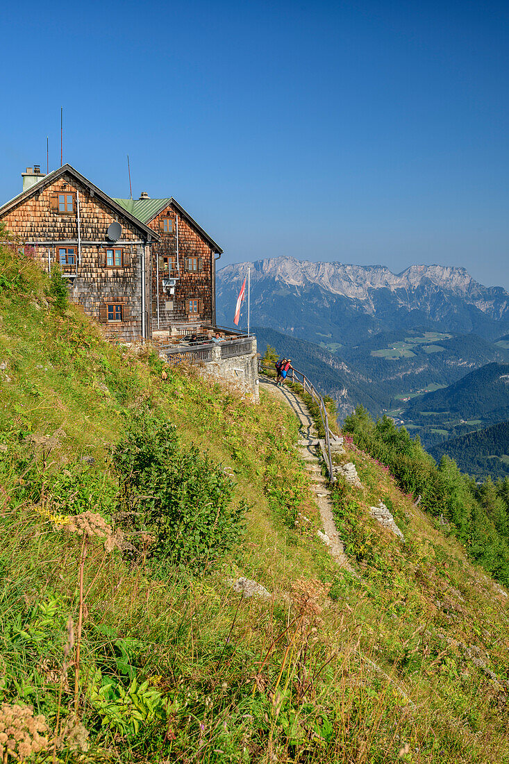 Two women while hiking face Purtschellerhaus, Untersberg Mountain in the background, Purtschellerhaus, High Goll, Berchtesgaden Alps, Upper Bavaria, Bavaria, Germany