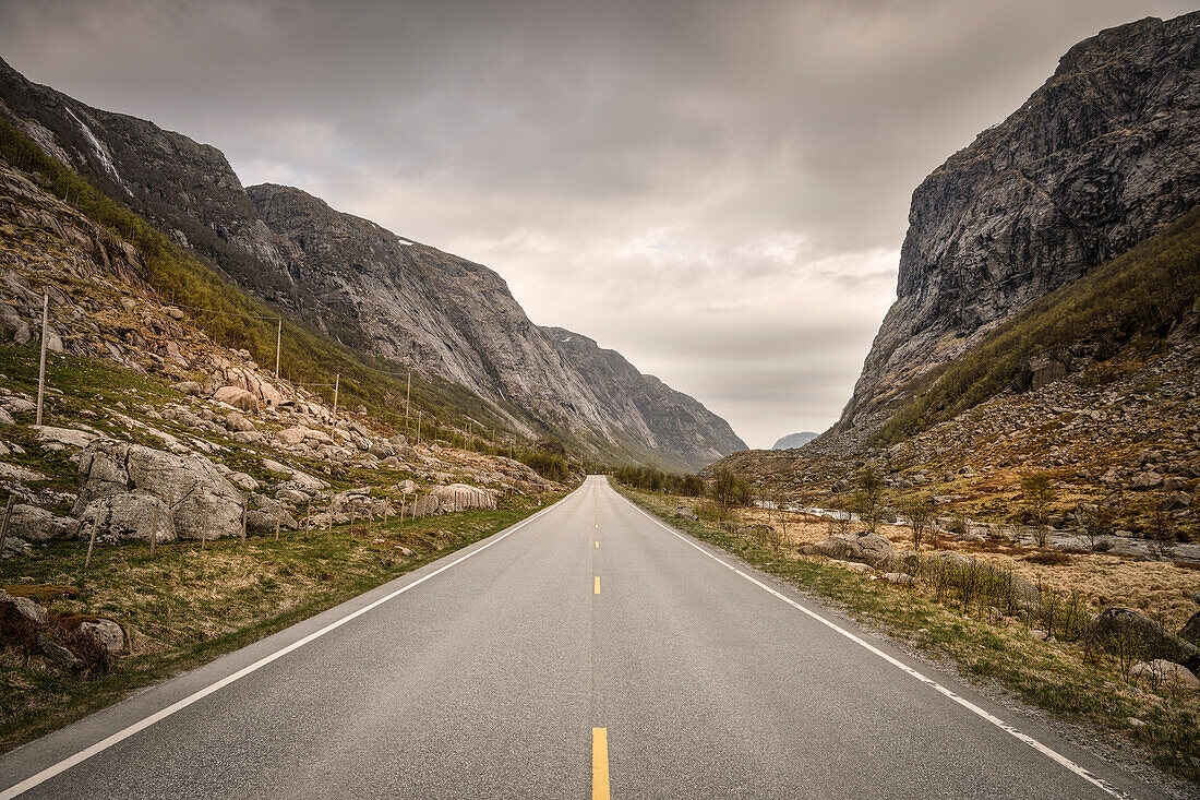 Straße führt durch tiefe Schlucht umgeben von Bergen, Norwegen, Skandinavien, Europa