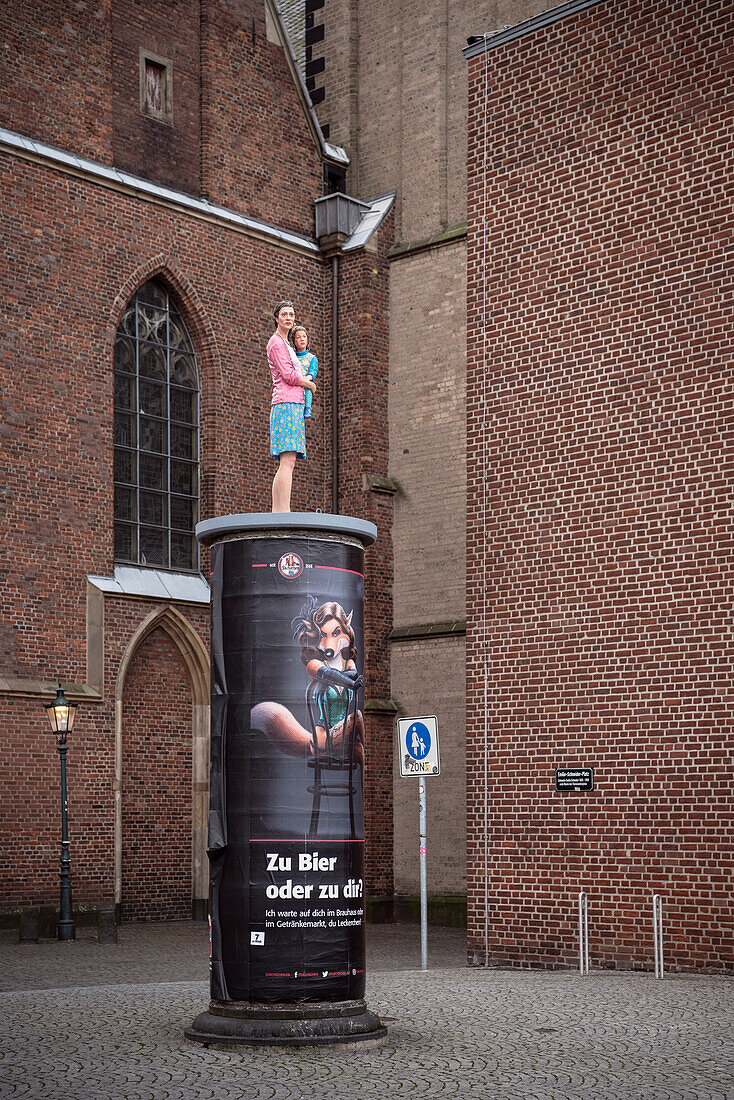 Frau mit Kind Figur steht auf Litfaßsäule vor Basilika St. Lambertus, Altstadt, Düsseldorf, Nordrhein-Westfalen, NRW, Deutschland