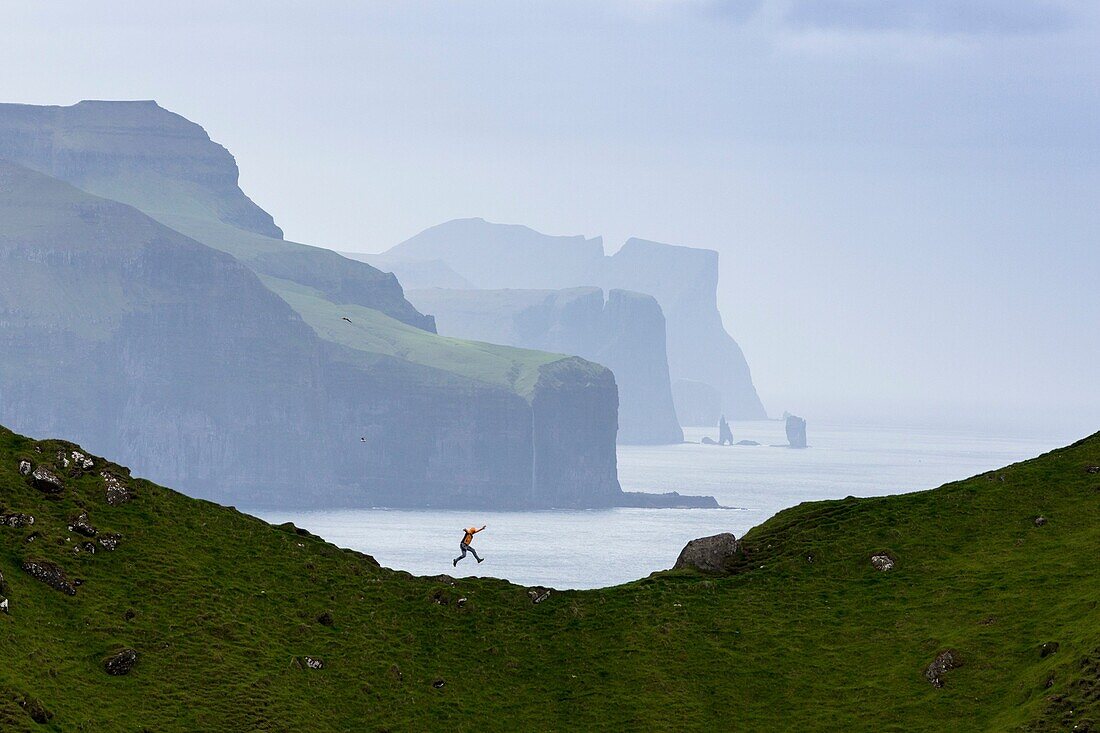 Man jumping on cliffs, Kalsoy island, Faroe Islands, Denmark.