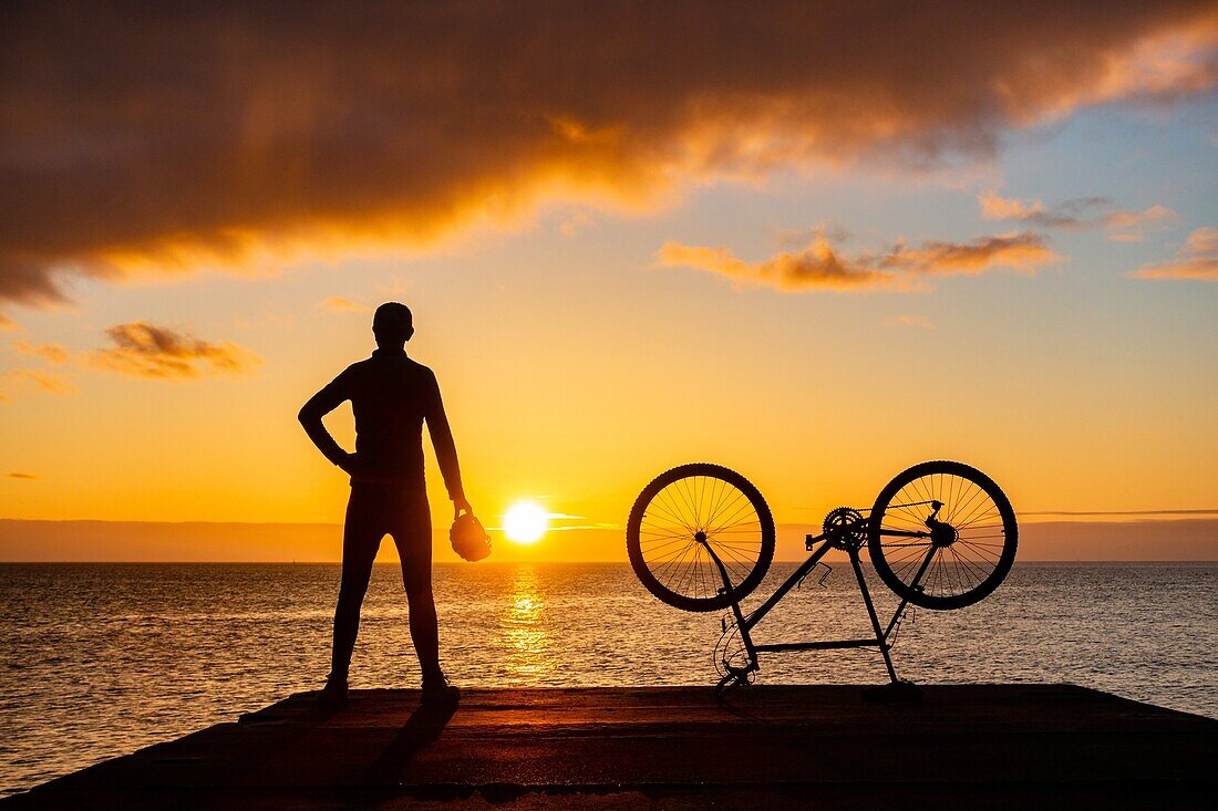 Seaton Carew, County Durham, north east England. United Kingdom. A mountain biker looks out over the North sea at sunrise.