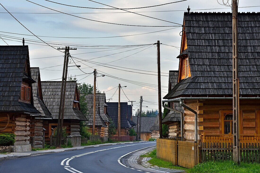 Holzhäuser entlang der Hauptstraße des Dorfes Chocholow, Region Podhale, Woiwodschaft Kleinpolen, Polen, Mitteleuropa.