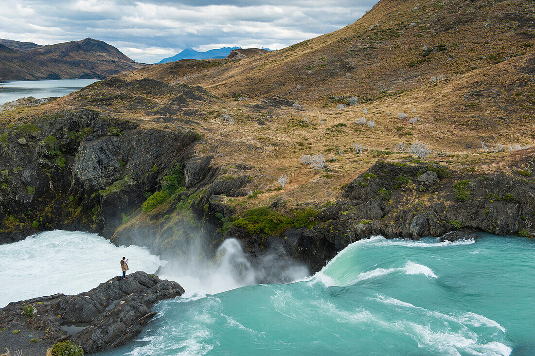 A visitor captures a photo at the Mirador Salto Grande waterfall, Torres del Paine National Park, Magallanes y de la Antartica Chilena, Patagonia, Chile, South America
