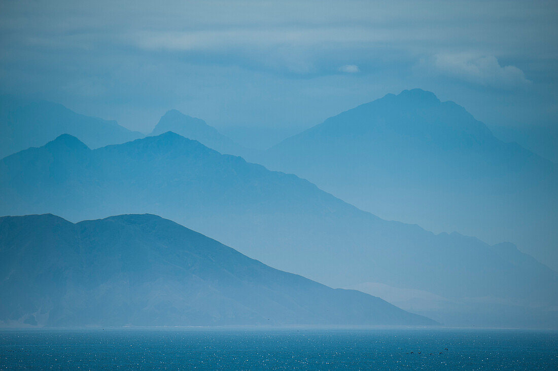 Küstenberge scheinen sich in verschiedenen Blautönen zu überlappen, nahe Trujillo, La Libertad, Peru, Südamerika
