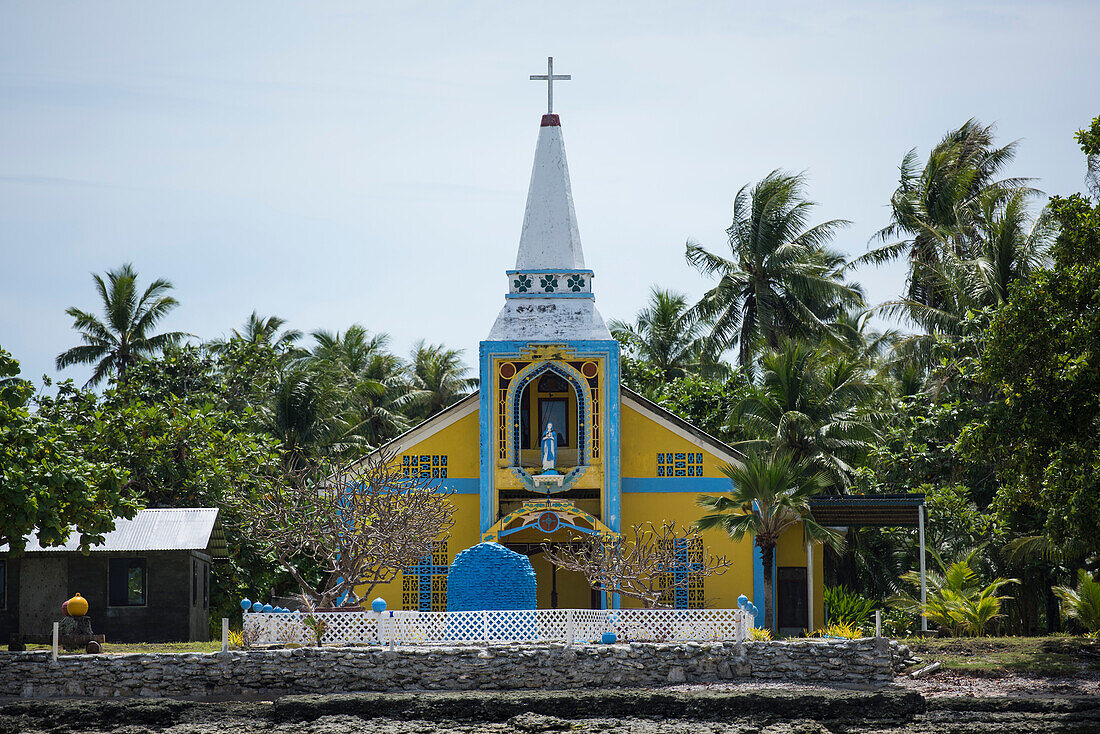 View of the brightly painted blue, white and yellow Catholic church surrounded by palm trees, Likiep Atoll, Ratak Chain, Marshall Islands, South Pacific