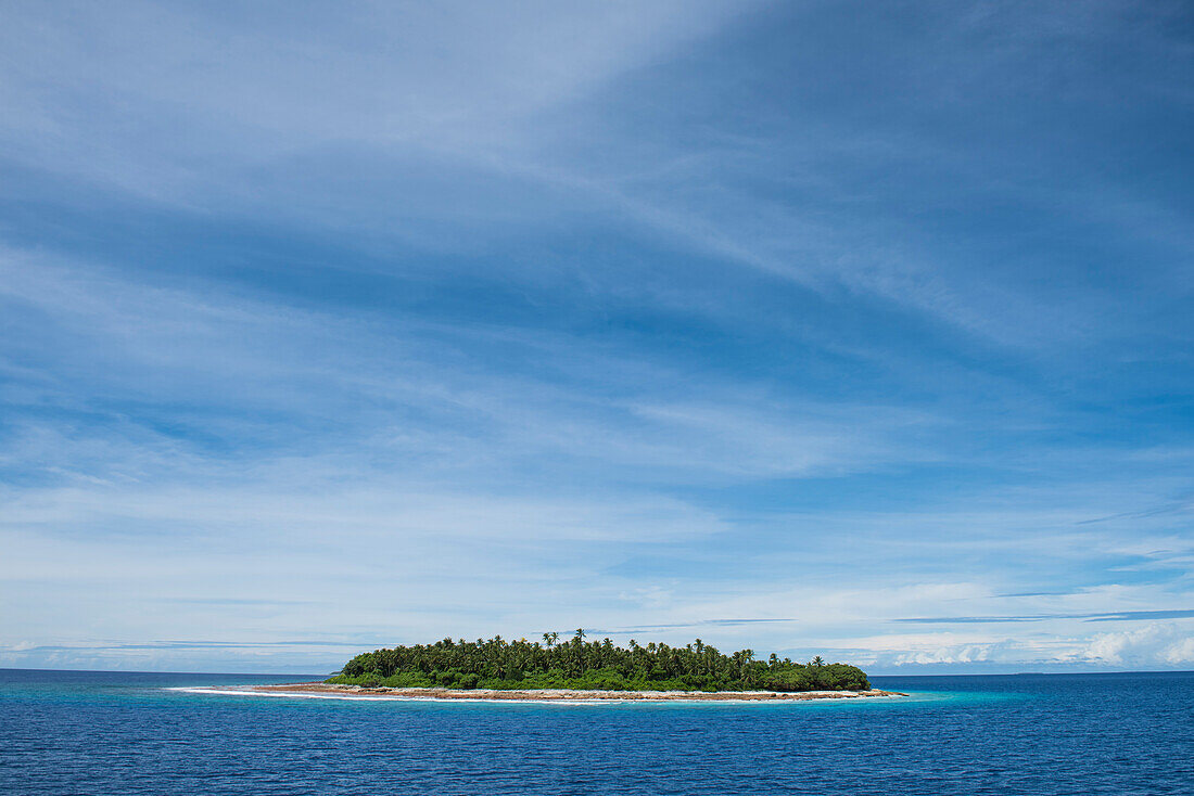 Blick auf eine kleine von Palmen bedeckte Insel, umgeben von türkisblauem und dunklerem blauen Wasser und von einem blauen Himmel mit dünnen Wolken dominiert, Likiep Atoll, Ratak-Kette, Marshallinseln, Südpazifik