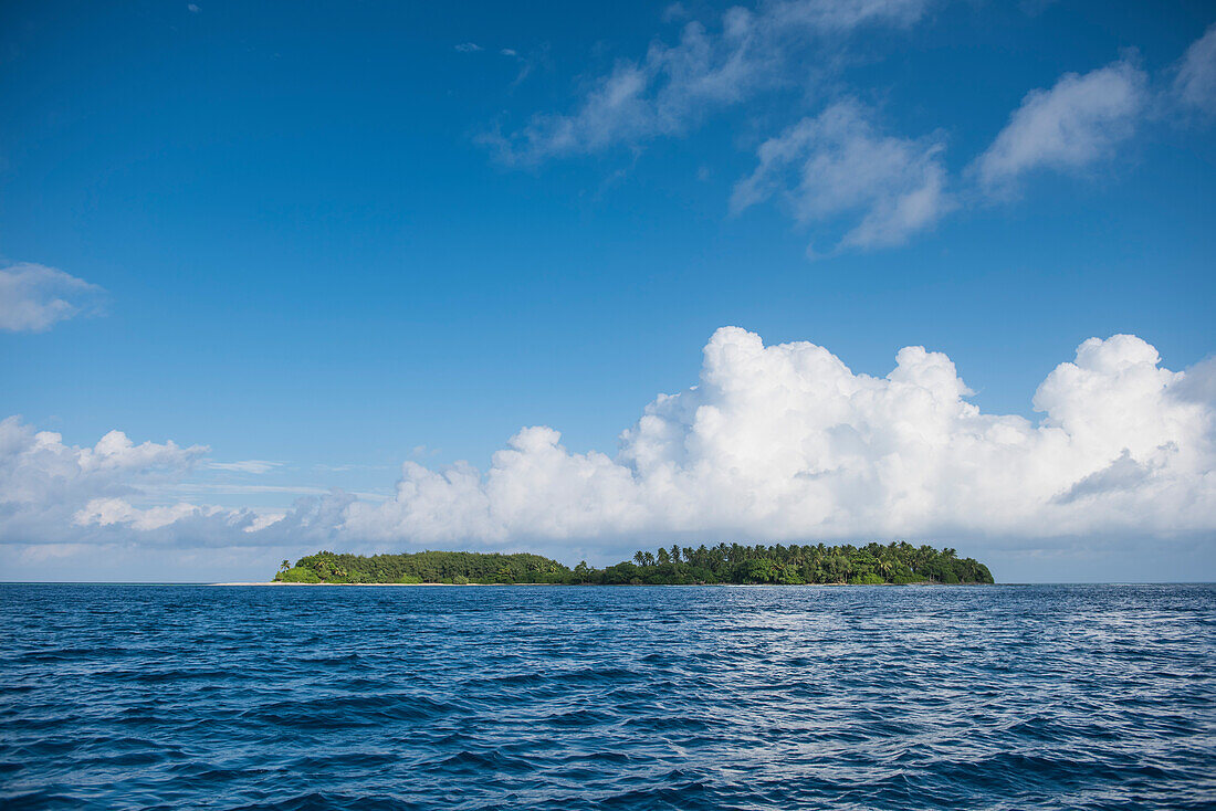 A long low-lying island lies in deep-blue seas under a sky dominated by large white clouds, Jabor Island, Jaluit Atoll, Ralik Chain, Marshall Islands, South Pacific
