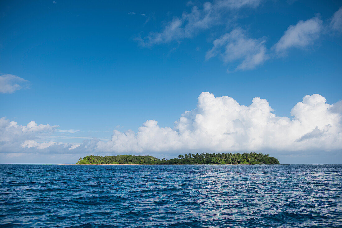 Eine lange tief liegende Insel liegt in tiefblauem Meer, dominiert von großen weißen Wolken, Jabor Island, Jaluit Atoll, Ralik-Kette, Marshallinseln, Südpazifik