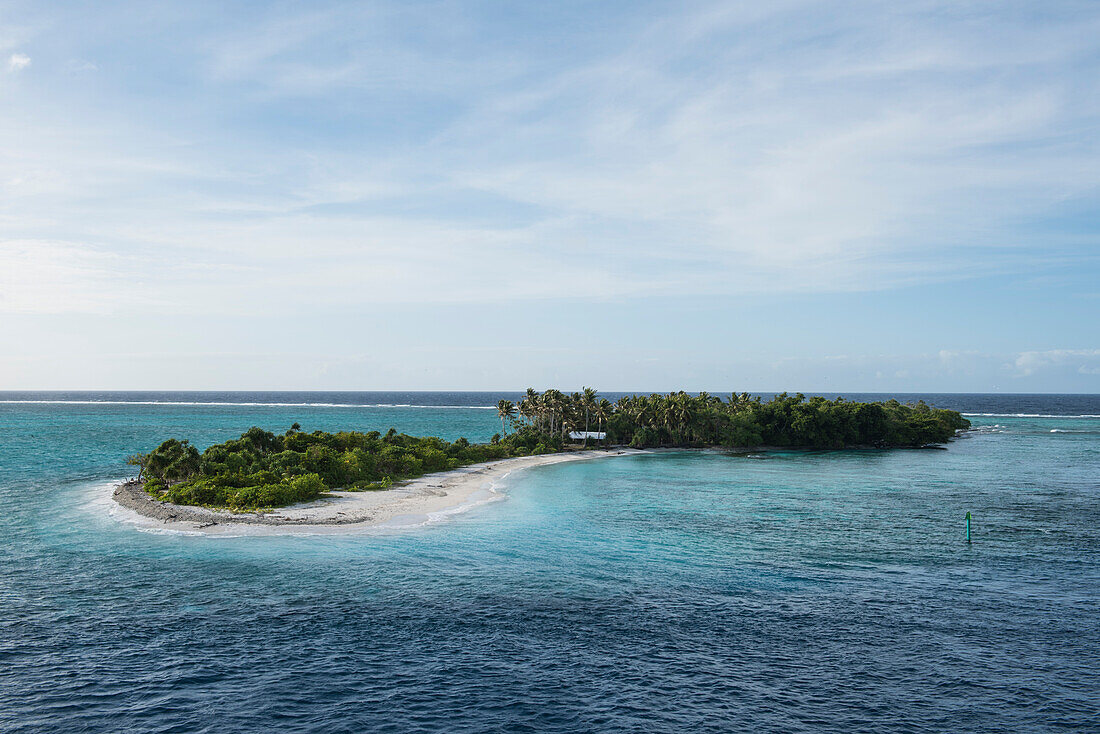 Eine lange und schmale Insel mit Palmen und Büschen und einem schmalen Streifen mit weißem Sand steht in türkisfarbenem Wasser unter einem leicht bewölkten Himmel, Mata Utu, Uvea Island, Wallis und Futuna, Südpazifik