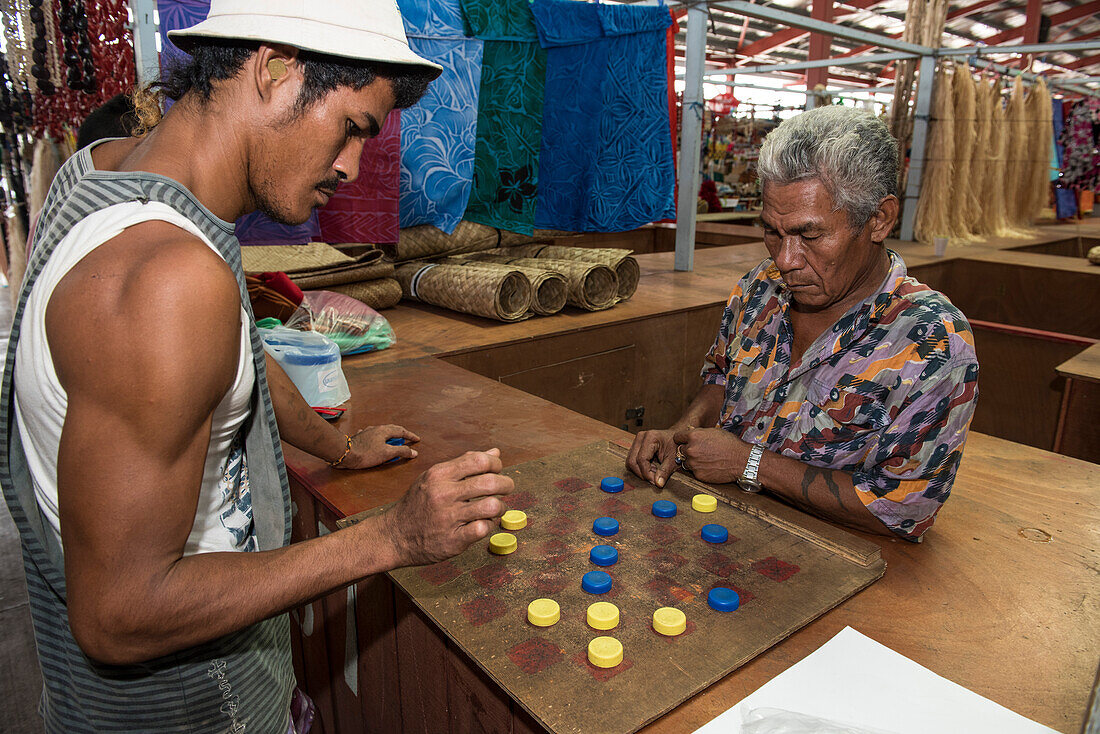 Zwei Marktarbeiter in einer Markthalle spielen Dame mit blauen und gelben Kronkorken, Apia, Upolu, Samoa, Südpazifik