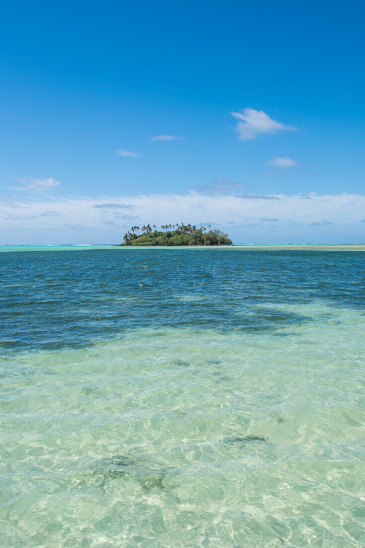 Blick auf eine winzige von Palmen bewachsene Motu-Insel mit viel Wasser im Vordergrund und blauem Himmel darüber, Rarotonga, Cookinseln, Südpazifik