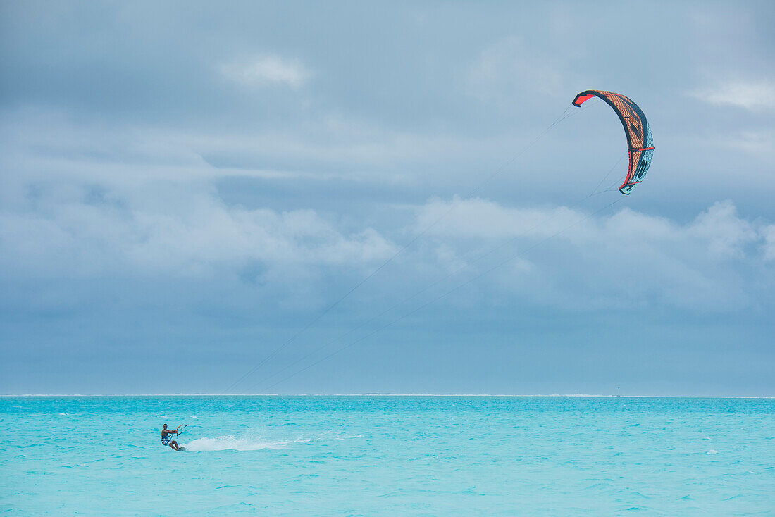 Ein Kite-Boarder durchquert an einem blau bewölkten Tag türkisblaues Wasser, Bora Bora, Gesellschaftsinseln, Französisch-Polynesien, Südpazifik