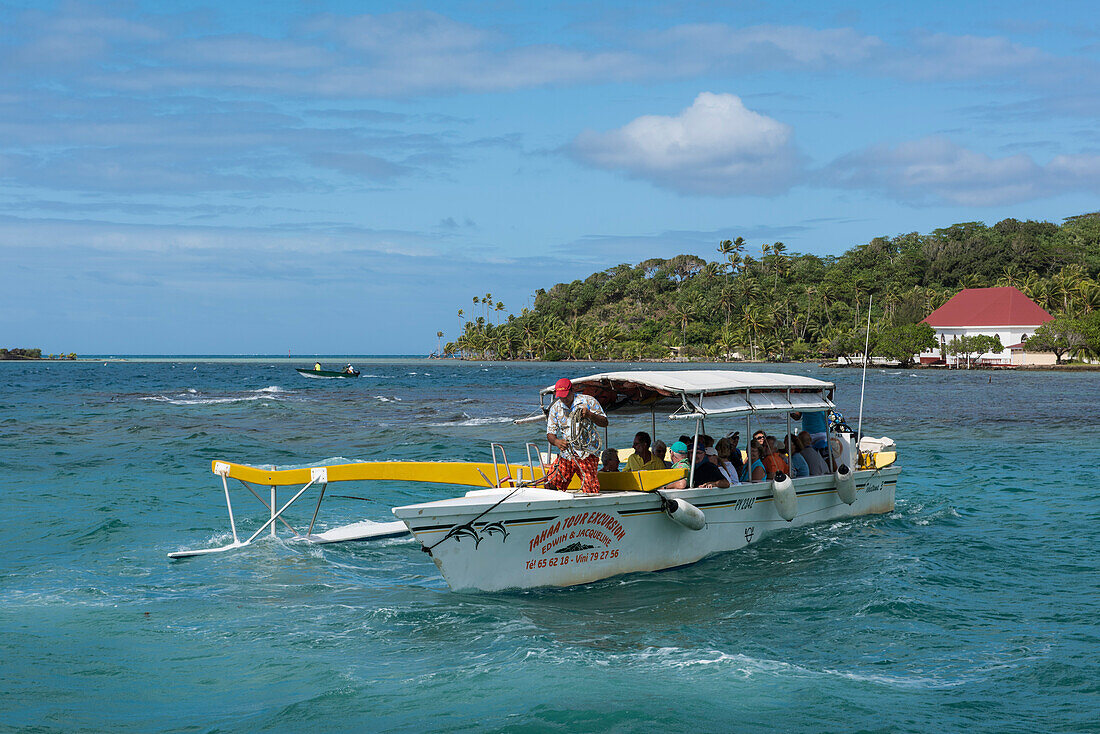Ein hölzernes Motorboot mit einem Ausleger bringt Touristen zu einem beliebten Schnorchelplatz, Taha'a, Gesellschaftsinseln, Französisch-Polynesien, Südpazifik