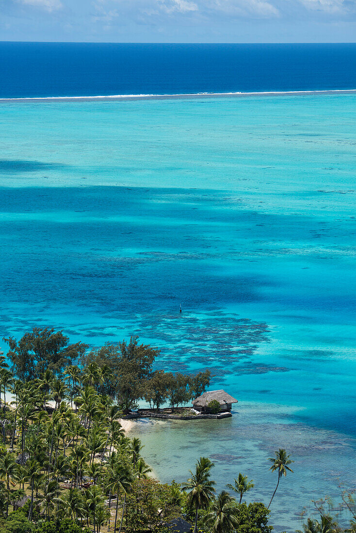 A bungalow stands on a small land-spit, surrounded on three sides by shallow turquoise water, Bora Bora, Society Islands, French Polynesia, South Pacific